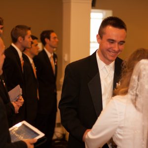 a groom smiles at his bride and a preacher stands beside them with a bible